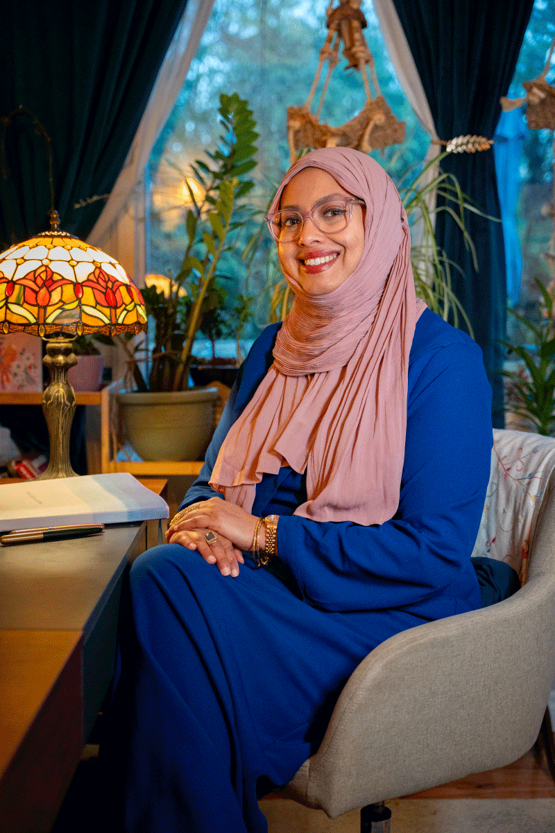 Shoilee sitting on her couch smiling